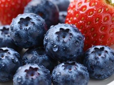 Macro shot of fresh, plump blueberries and strawberries with dew drops, bright clinical light