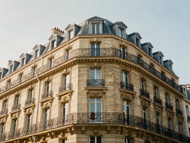 Wide architectural shot of a sunlit Parisian Haussmannian facade with classic wrought iron balconies, warm afternoon stone tones, 35mm lens editorial photography