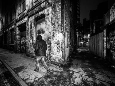 raw flash photography, high contrast black and white, gritty Birmingham urban environment, direct harsh light, 28mm wide-angle lens, industrial building facade, off-center subject