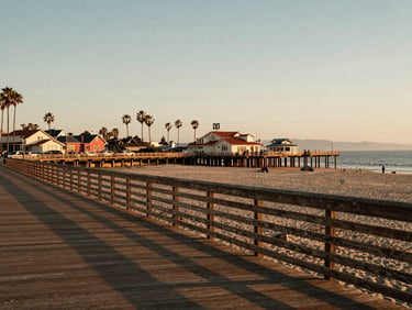 A beautiful golden hour view of the Imperial Beach pier from a beachside boardwalk, warm soft lighting, capturing a relaxed, local San Diego South Bay neighborhood feel.