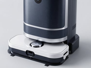 Sleek dark textured robotic cleaner with silver trim sitting in its multi-functional white OMNI station, high-contrast studio environment
