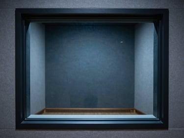 A pristine empty soundproofed recording booth seen through a double-glazed studio window, soft blue and gray tones, minimalist composition, sharp focus