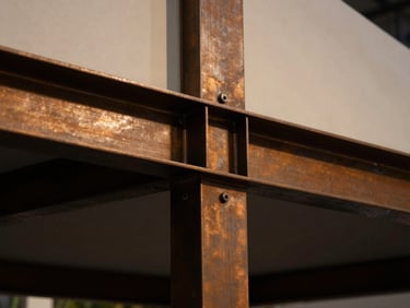 Extreme close-up of premium materials and architectural steel joints on a custom exhibition pavilion, dramatic warm lighting, deep shadows
