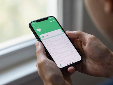 Medium shot of hands holding an Android phone showing a currency converter app with clean numeric input, natural window light, shallow depth on background
