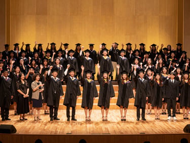 A wide cinematic shot of a grand graduation ceremony stage, warm golden lighting, students celebrating their achievements with families.