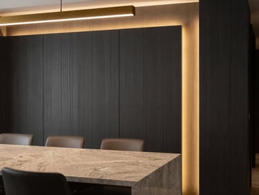 Interior detail of a modern dining room with fluted charcoal wall panels, warm gold architectural lighting, premium quartz countertops