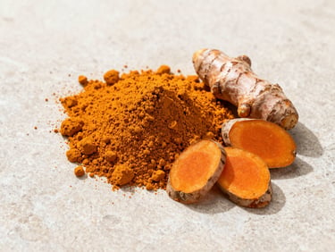 A structured flat-lay of vibrant orange turmeric powder beside raw sliced rhizomes on a clean light stone background, crisp natural lighting.