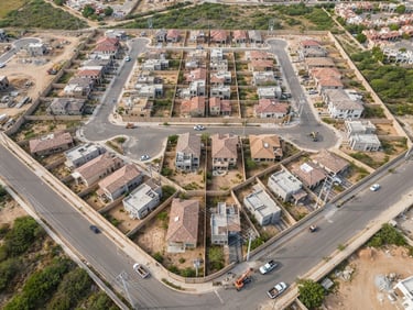 Overhead drone perspective of a planned housing layout showing concrete boundary walls and electrical infrastructure.