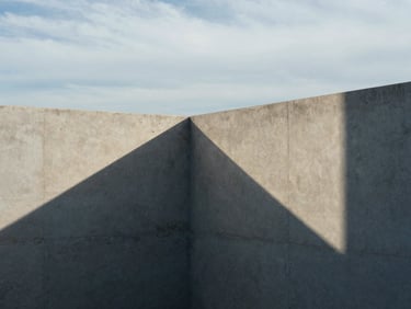 Structured geometric shadows on a minimalist concrete wall, overcast coastal daylight, architectural photography