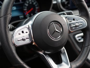 Extreme close-up of a high-performance Mercedes steering wheel, brushed platinum and hand-stitched charcoal leather, cold studio lighting, razor-sharp focus