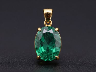 Close-up of a gold pendant featuring a natural unheated emerald, sharp facets, high-contrast lighting, dark background