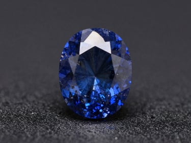 Macro shot of a rare blue sapphire crystal, unheated, showing natural growth patterns, dramatic spotlighting, deep charcoal background, 100mm lens.