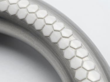 Close-up cutaway of a pneumatic pipe bend showing hexagonal white ceramic tiles lined precisely along the inner wear radius