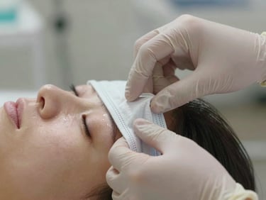 Close-up of hands in sterile gloves gently applying a clinical mask to clean skin, natural daylight, soft focus