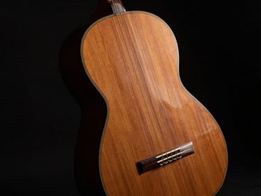 Chiaroscuro portrait of an antique classical guitar body, showing the elegant curves of Torres design, soft shadow