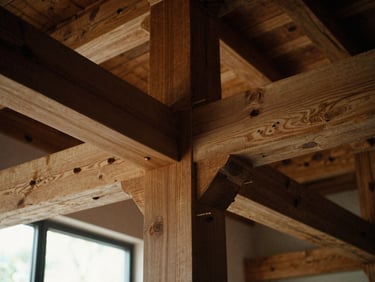 Close-up of exposed heavy timber structural framing, massive oak beams joined with wooden pegs under low-key side lighting.