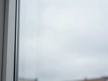 Close-up of perfectly clean, streak-free glass reflecting a bright, soft overcast sky, pristine and invisible