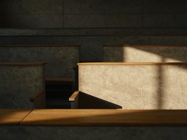 A close-up of a minimalist, architectural concrete lecture hall with dramatic side-lighting casting long shadows across empty rows of wooden desks, warm golden-hour light, cinematic 35mm photography.