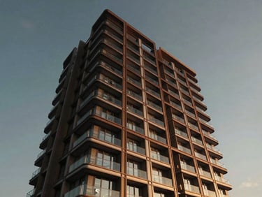 Cinematic low-angle drone shot of a modern luxury residential building facade in Istanbul during golden hour, bronze steel accents, glass balconies, dramatic lighting
