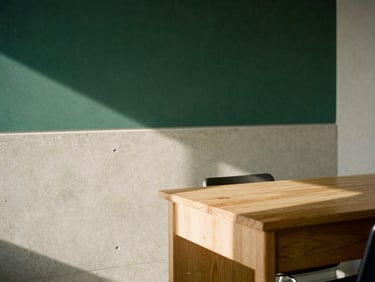 Architectural detail of a quiet, sunlit workspace with clean lines, concrete walls, and a single oak desk, natural shadows.