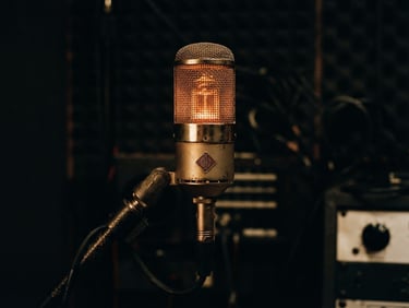 Close-up of a vintage tube microphone glowing with warm amber light in a dark recording studio, deep shadows, high-contrast analog texture, 35mm film