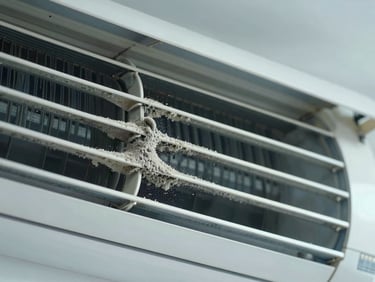 Close-up of dirty air conditioner cooling fins, thick grey dust and mold clogging the metal coils, harsh inspection light.