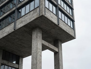 Brutalist concrete and steel structural column supporting a modern high-rise, sharp overcast shadows