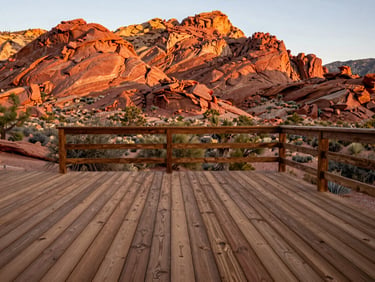 Warm editorial photograph of a beautifully finished wooden deck overlooking the Verde Valley red rocks, natural Arizona golden-hour light, earthy terracotta and juniper tones, sharp focus, 35mm lens