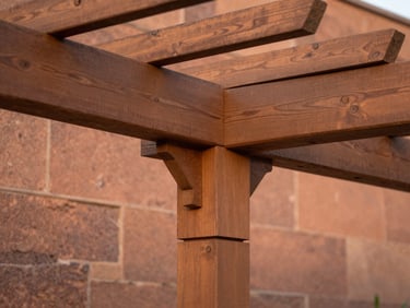 Macro architectural detail of a perfectly joined mortise and tenon timber connection in a custom outdoor pergola, warm terracotta stone wall in the background, sharp focus, 35mm lens.