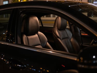 Close-up of a polished black luxury vehicle interior, focusing on leather seats and dashboard, subtle ambient amber lighting, 35mm