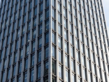 Architectural crop of a modern corporate skyscraper facade, sharp geometric steel and glass lines, crisp daylight, high contrast
