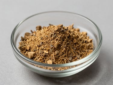 Close-up of loose ashwagandha root powder in a small glass dish on a neutral gray surface, cool north-facing daylight, fine texture visible, clinical ingredient detail photography, no warm tones
