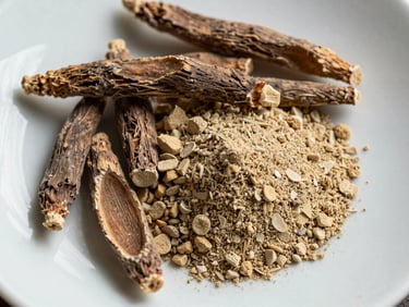 Extreme close-up overhead flat-lay of ashwagandha root pieces and fine powder on a clean white ceramic surface under cool even studio lighting, ingredient texture sharply in focus