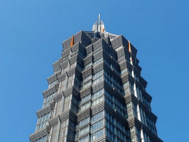 Abstract structural geometry of a modern steel skyscraper frame, looking straight up, bright blue sky, high-contrast lighting, sharp lines