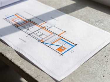 Tight macro shot of architectural blueprints laid out on a raw concrete table, sharp daylight casting hard linear shadows, minimalist composition