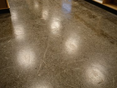 Overhead shot of a showroom floor, high-gloss epoxy with metallic aggregate, even artificial light, no people or products, surface reflection detail visible