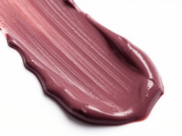 Macro shot of rich, velvety plum-colored lipstick texture being swiped across a clean surface, dramatic studio lighting highlighting the creamy consistency.
