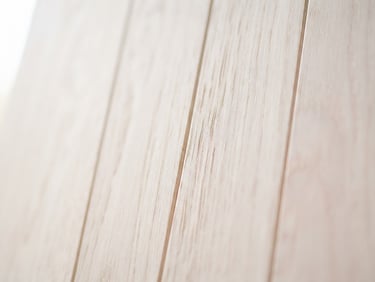 Close-up of light-toned pastel wood grain with soft, diffused morning light, shallow depth of field, clean vertical lines.