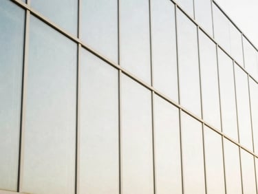Abstract geometric composition of architectural glass panels reflecting bright daylight, clean lines, minimalist structure, high-key exposure.