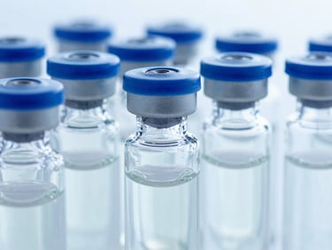 Extreme close-up of sterile glass vials containing clear IVIG solution, crisp clinical lighting, royal blue accents