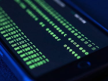 Macro close-up of a ruggedized Android screen displaying scrolling green terminal compilation lines, cool blue ambient light, high-contrast 35mm focus.