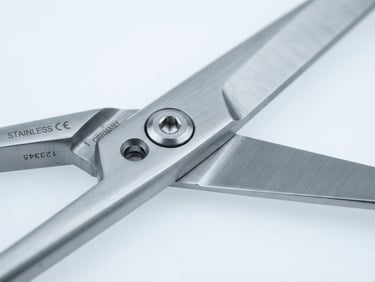 Extreme macro close-up of a surgical scissor joint, showing fine machining and satin finish, sterile blue backdrop, cool studio lighting, sharp detail, bleeding to the right edge.