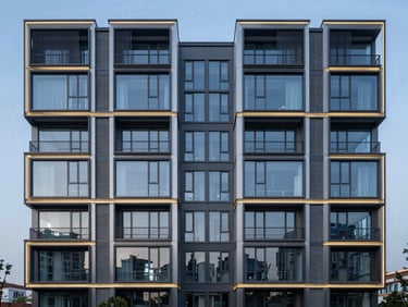 A wide panoramic view of a completed modern building facade with high-end steel and glass finishes during the quiet blue hour.