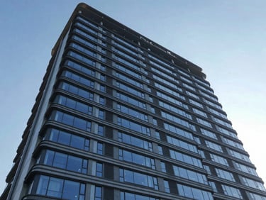 Wide-angle architectural photograph of a newly completed commercial high-rise facade, crisp daylight, cool blue and slate tones, high clarity, 35mm.