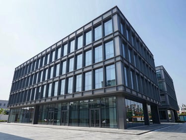 Wide-angle architectural photograph of a modern commercial office building with clean steel frames and glass facade, crisp daylight, cool blue slate tones.