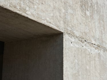 Extreme close-up of raw board-formed concrete texture under harsh midday Baja sun, casting deep shadows in the wood grain grooves, sharp architectural angle.