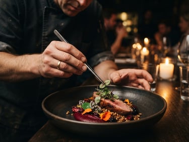 Moody editorial close-up of a chef's hands carefully placing microgreens with tweezers onto an artfully plated dish, warm candlelit background, deep shadows, 35mm.