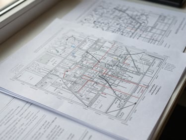 Close overhead shot of annotated conflict-mapping documents spread across a desk, handwritten margin notes visible, natural window light falling from the left side, no people present