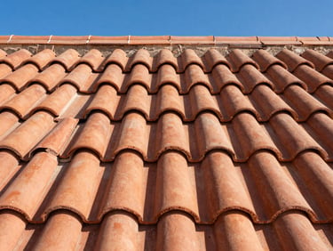 Close-up of clean terracotta roof tile alignments under intense desert sun, crisp shadows, sharp architectural detail.