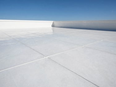 High-contrast architectural photo of a seamless white TPO flat roof weld, reflecting harsh sunlight under a clear blue sky.